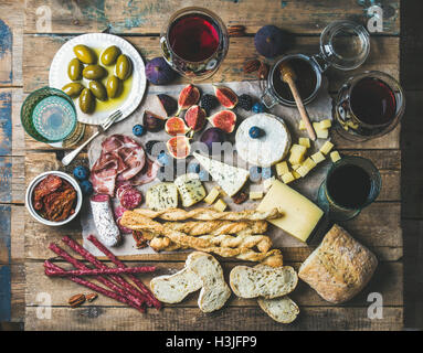 Vin et snack-set avec différents vins dans les verres, variété de viande, pain, tomates séchées, miel, olives vertes, figues, noix et b Banque D'Images