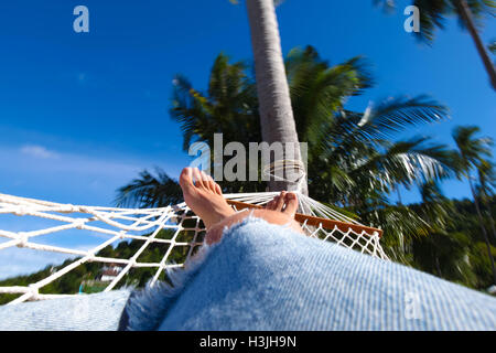 Vous pourrez vous détendre sur la plage en hamac, vue sur les jambes et les arbres palme Banque D'Images