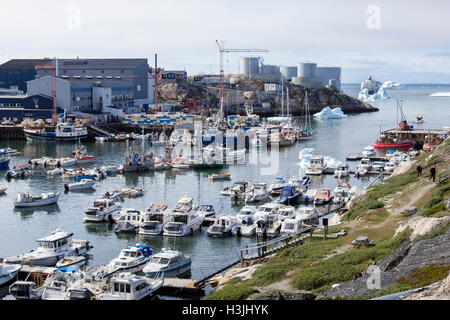 Grands et petits bateaux de pêche amarrés dans le port avec le bâtiment de l'usine de poisson bleu sur le quai. L'ouest du Groenland Ilulissat Banque D'Images