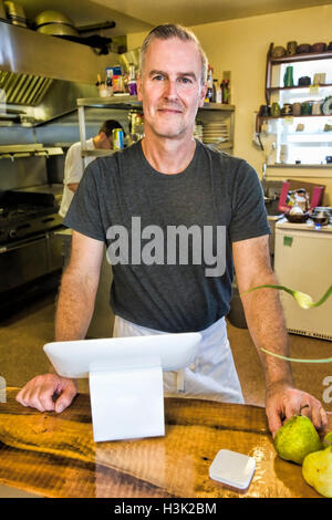 Cafe owner smiling derrière compteur d'entretien Banque D'Images