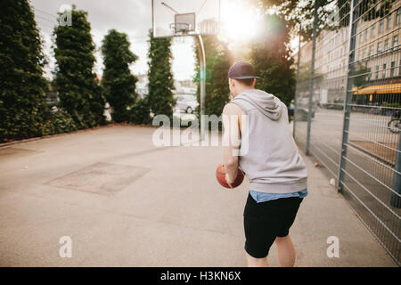 Vue arrière Vue d'un joueur de streetball jouer au basket-ball. Jeune homme jouant au basket-ball sur une cour. Banque D'Images