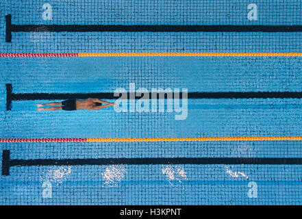 Vue de dessus coup de jeune homme faire des longueurs dans une piscine. Le nageur dans l'eau. Banque D'Images