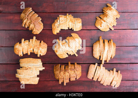 Vue du haut vers le bas sur 9 tranches de pain de blé de spécialité et la farine blanche pains dans la formation échelonnée sur bac en bois teinté foncé Banque D'Images