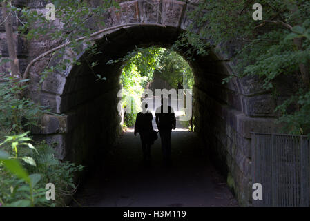 Silhouettes d'habitants de la ville dans le contexte de l'entrée au pont tunnel dans le West End de Glasgow dans le parc Banque D'Images