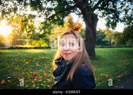 Jeune femme émotionnelle avec bouquet de feuilles faire une grimace en parc d'automne. Concept de l'automne Banque D'Images