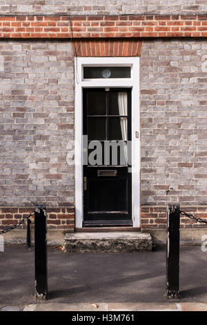 Porte en bois extérieure noire victorienne avec panneaux de verre sur un mur de brique gris classique Banque D'Images