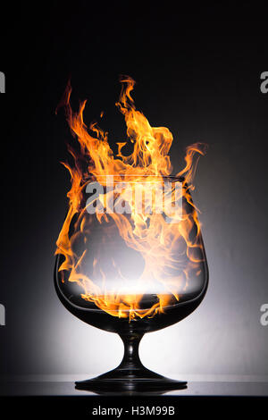 Image composite de verre en feu avec des flammes déchaînées sur un fond noir Banque D'Images