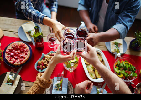 Friends toasting with red wine sur table servi Banque D'Images