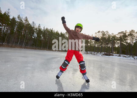 L'équilibrage de garçon alors que le patin à glace sur un lac gelé, Gavle, Suède Banque D'Images