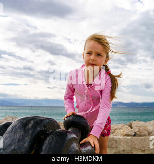 Cute little girl avec ancre de bateau sur la mer, le temps orageux Banque D'Images