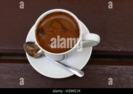 Noir fraîchement moulu turc terrain naturel brun café mousse mousse blanc en pleine tasse avec soucoupe et cuillère en métal sur des ta Banque D'Images