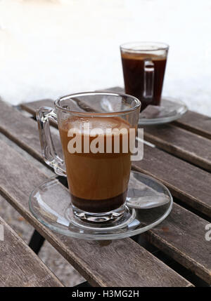 Deux fraîchement moulu turc terrain naturel café, noir et au lait, en plein verre transparent avec tasses et soucoupe metal Banque D'Images