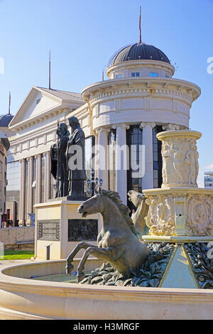 Statues de Skopje y compris fontaine avec des chevaux avec Musée de l'archéologie en arrière-plan. Banque D'Images