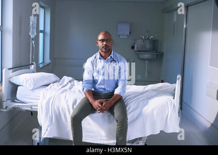 Portrait of mature médecin homme assis sur le lit d'hôpital à ward Banque D'Images