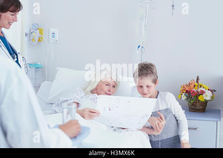 Senior female patient in hospital bed looking à Grandson's dimensions Banque D'Images