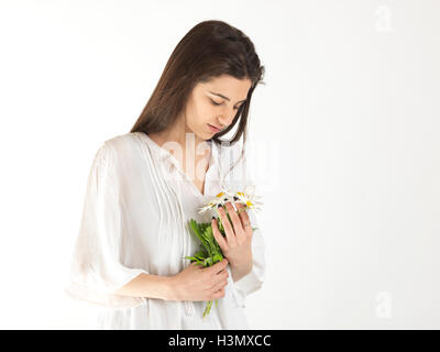 Studio portrait of young woman gazing at bouquet de marguerites Banque D'Images