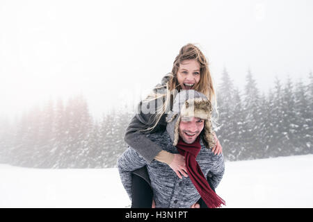 Couple in love, man giving woman piggyback. Nature de l'hiver. Banque D'Images