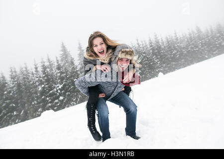 Couple in love, man giving woman piggyback. Nature de l'hiver. Banque D'Images