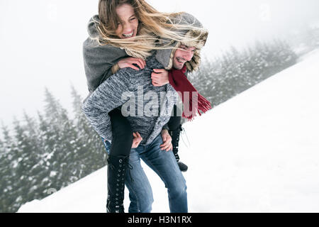 Couple in love, man giving woman piggyback. Nature de l'hiver. Banque D'Images