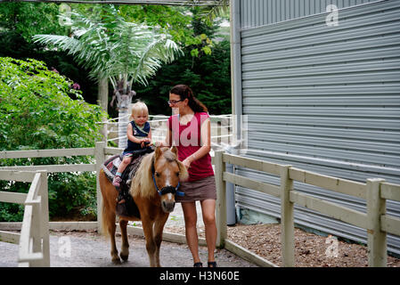 Une fière maman et sa fille âgée de deux ans sur son premier tour de poney Banque D'Images