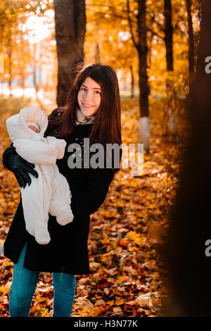 Jeune mère avec son petit bébé sur part in autumn park Banque D'Images