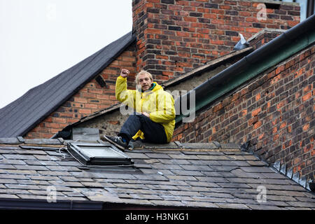 Manchester, UK. 11 octobre, 2016. Un jeune homme, Chris de Salford, grimpa sur le toit de la maison en fonction du pont Ducie Street Miller à 8-o-réveil ce matin pour protester contre l'expulsion de 30 personnes sans abri qui ont été accroupis dans l'immeuble pendant plusieurs semaines. Les agents d'application de la Haute Cour acquise entrée du bâtiment, propriété de la société coopérative, tôt ce matin, d'expulser les squatters qui ont été défiant un haute cour d'expulsion. Crédit : Dave Ellison/Alamy Live News Banque D'Images