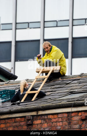 Manchester, UK. 11 octobre, 2016. Un jeune homme, Chris de Salford, grimpa sur le toit de la maison en fonction du pont Ducie Street Miller à 8-o-réveil ce matin pour protester contre l'expulsion de 30 personnes sans abri qui ont été accroupis dans l'immeuble pendant plusieurs semaines. Les agents d'application de la Haute Cour acquise entrée du bâtiment, propriété de la société coopérative, tôt ce matin, d'expulser les squatters qui ont été défiant un haute cour d'expulsion. Crédit : Dave Ellison/Alamy Live News Banque D'Images