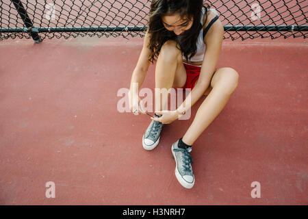 Jeune femme attacher les lacets sur terrain de basket-ball Banque D'Images