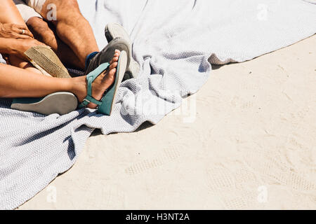 Senior couple sitting on picnic blanket on beach, low section, Long Beach, Californie, USA Banque D'Images