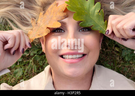 Femme couchée sur une prairie avec son visage couvert de feuilles Banque D'Images