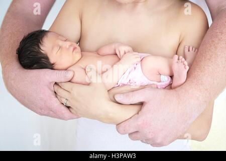 Parution du modèle. Les parents cradling newborn baby girl. Banque D'Images