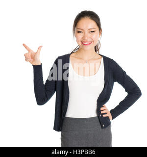 Portrait de jeune fille asiatique de pointer du doigt quelque chose et souriant, isolé sur fond blanc. Banque D'Images