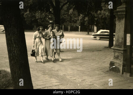 Allemagne - circa 1950 : Trois femmes descendre le trottoir sur l'arrière-plan de voitures passant et arbres Banque D'Images