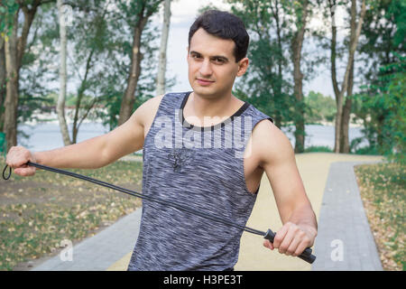 Jeune homme remise en forme avec une corde se prépare à l'exercice dans la formation à l'extérieur du parc Banque D'Images