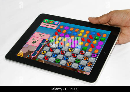 Un homme maintenant l'iPad avec Candy Crush saga game Banque D'Images