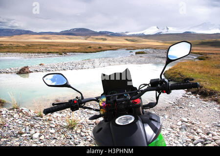 Moto enduro traveler debout sur la montagne de banque de pierre rivière blanche près d'un gué sur l'arrière-plan de sommets enneigés Banque D'Images