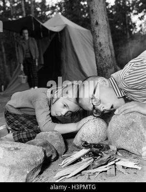 1950 Garçon Fille soufflant sur des braises DE FEU DE LA TENTATIVE DE DÉMARRAGE DE FEU Banque D'Images