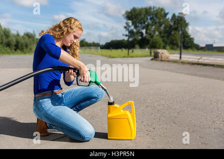 Dutch femme jaune peut remplir avec de l'essence à l'extérieur du flexible Banque D'Images