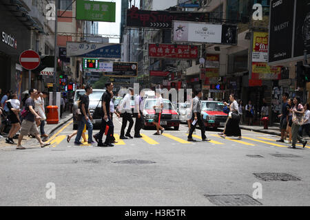 Le peuple chinois crossing road dans le district central, l'île de Hong Kong, Chine, Asie. Banque D'Images