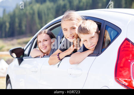 Jeune femme et ses enfants assis dans une voiture et regarder dehors à partir de windows. Voyages en famille image en arrière-plan Banque D'Images