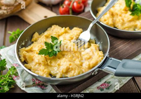 Oeufs brouillés aux fines herbes et du pain fait maison, sur deux poêles à frire Banque D'Images