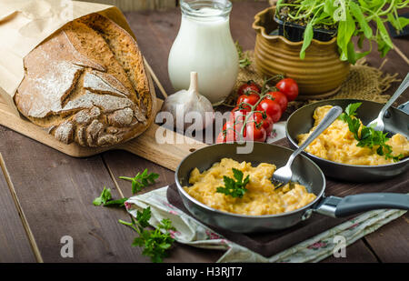 Oeufs brouillés aux fines herbes et du pain fait maison, sur deux poêles à frire Banque D'Images