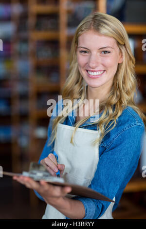 Le personnel female writing on clipboard in supermarket Banque D'Images