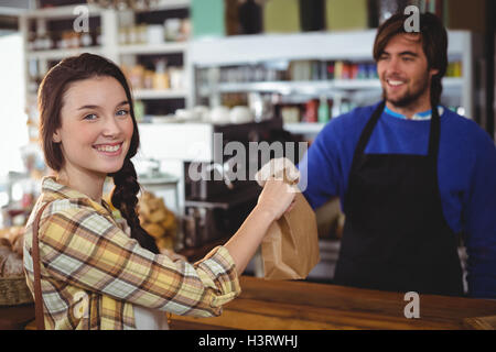 Woman receiving colis provenant de serveur au comptoir Banque D'Images