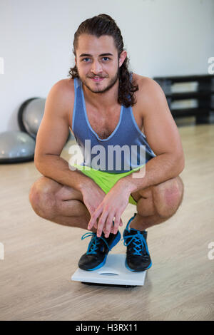 Portrait of smiling man sitting on weight scale Banque D'Images