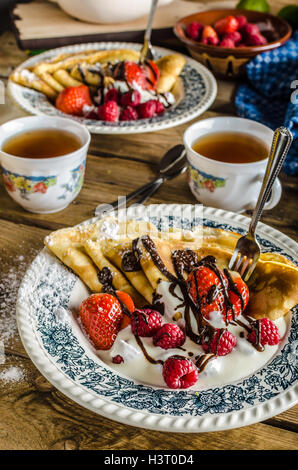 Crêpes maison aux fruits rouges, crème fraîche et chocolat noir, saupoudré de sucre, avec thé au citron, plat tchèque classique Banque D'Images