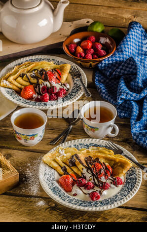 Crêpes maison aux fruits rouges, crème fraîche et chocolat noir, saupoudré de sucre, avec thé au citron, plat tchèque classique Banque D'Images