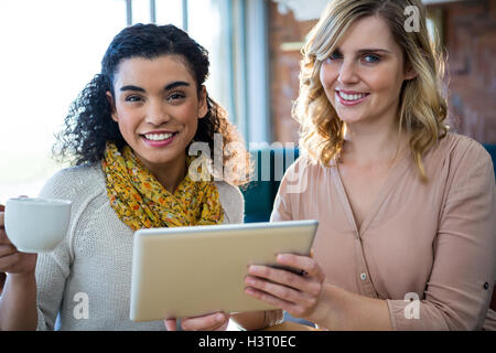 Female friends using digital tablet while having coffee Banque D'Images