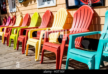 Chaises Adirondack orange et jaune sur le trottoir Banque D'Images