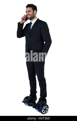 Businessman sur hoverboard talking on mobile phone Banque D'Images